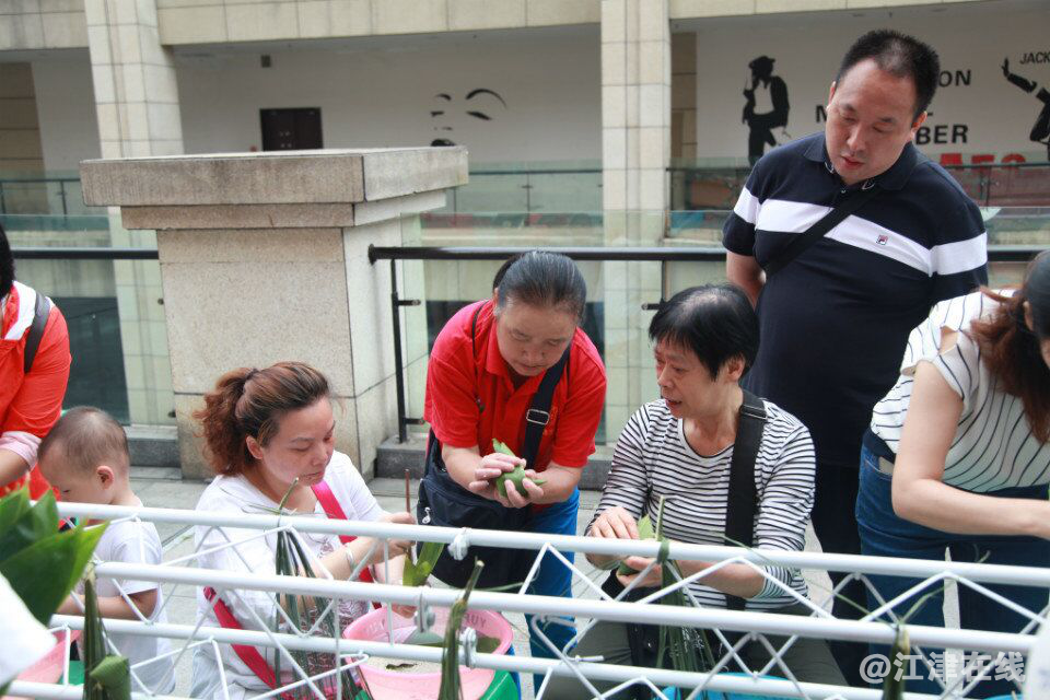 图为家长们在学习如何包粽子.png